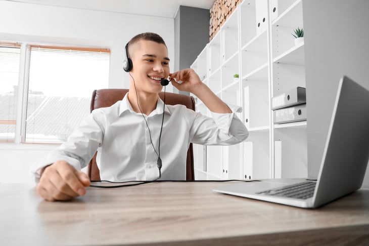 Young man wearing a headset working at a laptop